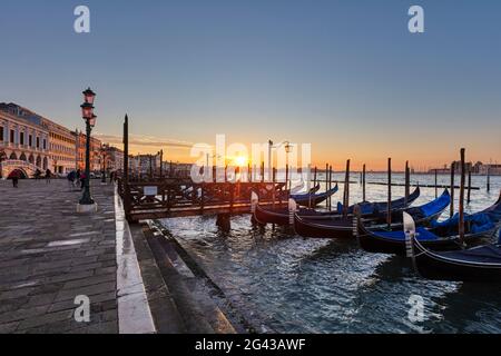 Gondole di fronte a Riva degli Schiavoni con alba sullo sfondo a Venezia, Veneto, Italia Foto Stock