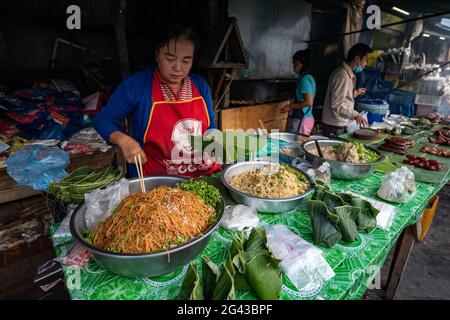 Donna prepara prelibatezze avvolte in foglie di banana per il mercato mattutino, Luang Prabang, provincia di Luang Prabang, Laos, Asia Foto Stock