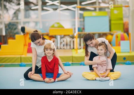 Bambini che fanno esercizi di stretching in palestra presso l'asilo o la scuola elementare. Concetto di sport e fitness per bambini. Foto Stock