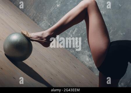 Giovane ragazza professionale ginnastica donna gamba primo piano ginnastica ritmica con palla in studio Foto Stock