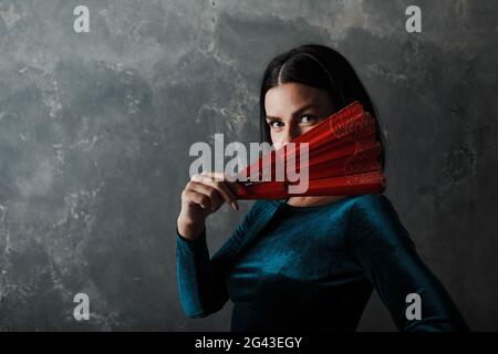 Giovane adulta spagnola donna che balla flamenco su sfondo grigio vintage Foto Stock