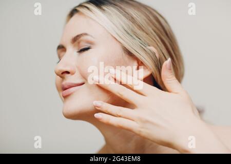 Olio cosmetico gelatina reale applicare con pipetta sul viso di giovane donna adulta Foto Stock