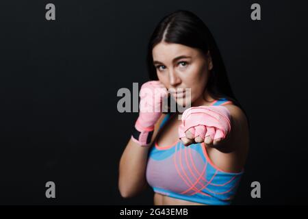 Sportivo muay thai donna boxer in posa in studio di formazione su sfondo nero. Foto Stock