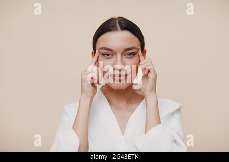 Giovane bella donna che fa faccia costruire ginnastica facciale self massage ed esercizi di ringiovanimento Foto Stock