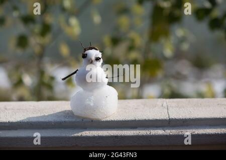 Pupazzo di neve su una recinzione con albero Foto Stock