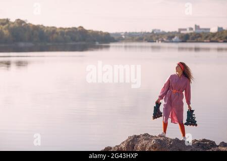 Giovane donna riccia che va a pattinare al parco. Foto Stock