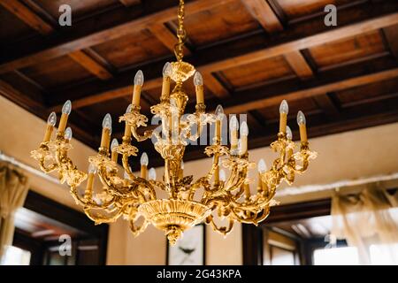 Lampadario in oro con lampade a candela sul soffitto. Foto Stock