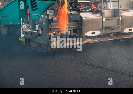 Asfaltatura. Lastricatore macchina. La costruzione di nuove strade. Foto Stock