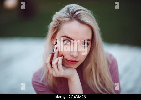 Giovane ragazza piuttosto pittore tracciare nel parco. Close up ritratto con spazzole. Foto Stock