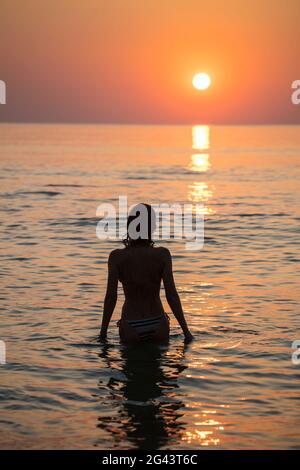 Silhouette di giovane donna in acqua di fronte alla spiaggia di Ong Lang al tramonto, Ong Lang, Phu Quoc Island, Kien Giang, Vietnam, Asia Foto Stock