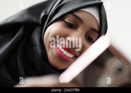 Afro girl usa un telefono cellulare e naviga nei social media durante una pandemia Foto Stock