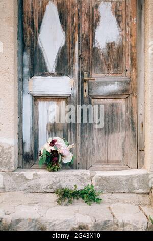 Bouquet nuziale di peonie bianche e rosa, rose, rami di eucalipto, gigli di calla e carciofi decorativi vicino all'anc Foto Stock