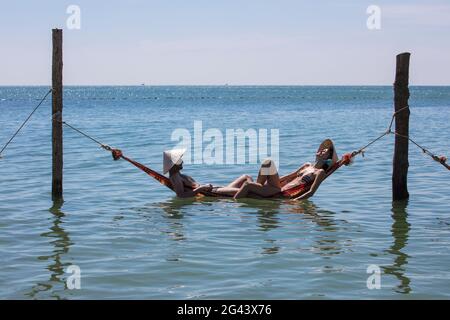 Coppia rilassante in un'amaca galleggiante al Chez Carole Phu Quoc Resort sulla spiaggia di Ong Lang, vicino a Cua Can, Phu Quoc Island, Kien Giang, Vietnam, Asia Foto Stock