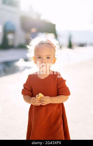 Una bambina dolce sta tenendo un pirogi di mela vicino la fontana nel parco Foto Stock