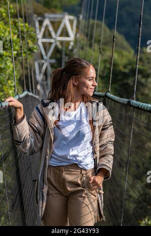 Giovane donna sul ponte sospeso di Canopy Walkway, Nyungwe Forest National Park, Provincia Occidentale, Ruanda, Africa Foto Stock