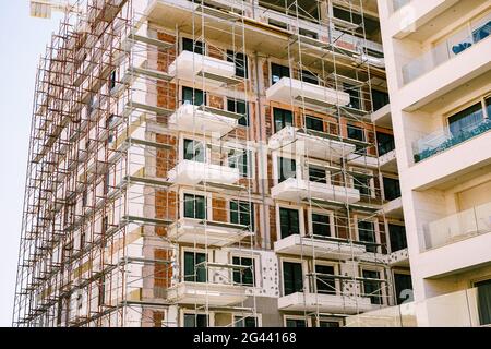 Impalcatura intorno ad un alto e moderno edificio in costruzione Foto Stock