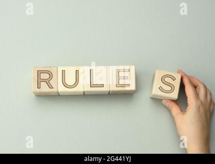 Blocchi di legno con le regole di iscrizione su uno sfondo grigio, la mano tiene un cubo. Il concetto di stabilire i confini e cond Foto Stock