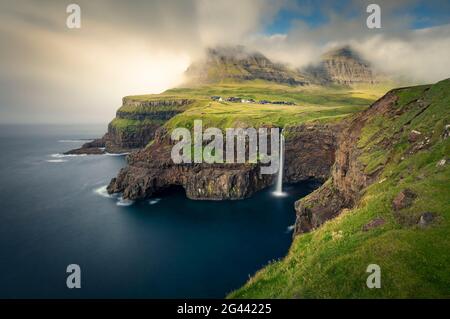 Cascata di Múlafossur con villaggio di Gásadalur sull'isola di Vagar, Isole Faroe Foto Stock