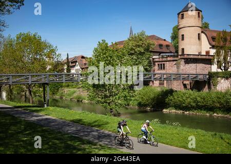 Ciclisti in pista lungo il Tauber con l'ex Corte principesca e Torre Bianca delle mura della città alle sue spalle, Wertheim, Spessart-Mainland, Franco Foto Stock