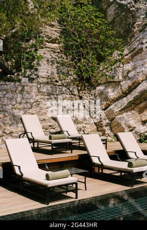 Lettini a bordo piscina ai piedi della montagna. Foto Stock