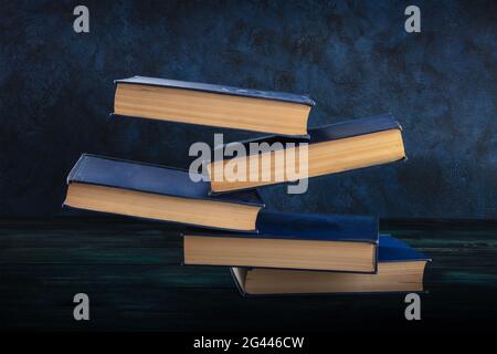 Libri che cadono sulla scrivania su sfondo blu Foto Stock