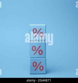 Blocchi di legno con percentuale su sfondo blu. Il concetto di riduzione o aumento dei prezzi Foto Stock