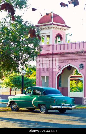 Classica auto verde di fronte a una porta rosa in stile arabo a Cienfuegos, Cuba Foto Stock