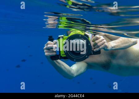 Foto subacquea dell'uomo con la fotocamera Panasonic Lumix con custodia subacquea mentre fai snorkeling nella laguna di Bora Bora, Bora Bora, Isole Leeward, Fr Foto Stock