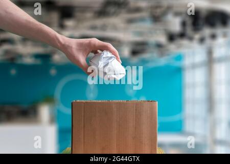 gettare a mano il pezzo di carta sgualcito nel cestino Foto Stock