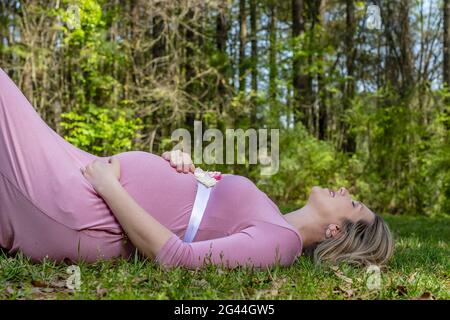 Una meravigliosa donna incinta incandescente posa in un ambiente esterno Foto Stock