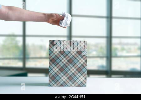 gettare a mano il pezzo di carta sgualcito nel cestino Foto Stock