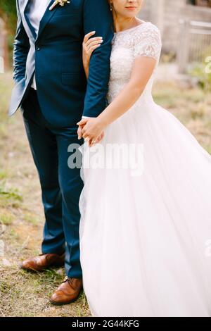 La sposa e lo sposo si abbracciano, la sposa tiene la mano dello sposo e si abbracca delicatamente Foto Stock