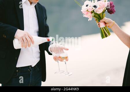 L'uomo sta versando lo champagne in due bicchieri per celebrare il impegno Foto Stock