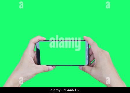 Smartphone maschio a mano con schermo verde isolato su sfondo verde. Foto Stock