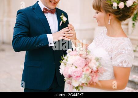 La sposa mette un anello sul dito dello sposo e. tiene un bouquet nelle sue mani durante la cerimonia nuziale Foto Stock