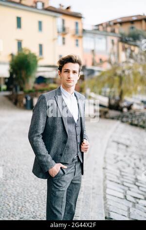 Groom si trova sulle ciottoli della strada di Varenna sullo sfondo di vecchie ville. Lago di Como Foto Stock