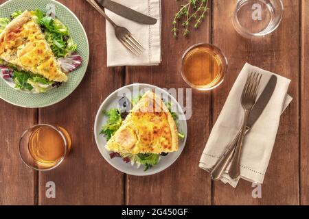 Fette di quiche francesi con salmone, con foglie di insalata verde, timo e vino bianco Foto Stock