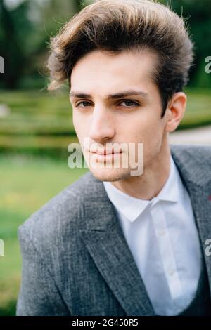 Ritratto di uno sposo giovane ed elegante in tuta grigia dall'aspetto elegante alla fotocamera Foto Stock