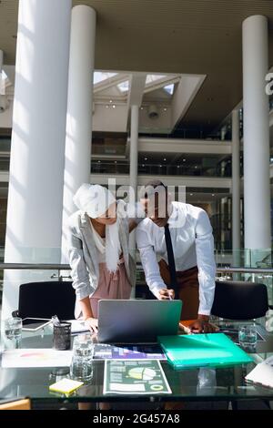 Maschio e femmina dei dirigenti a discutere su computer portatile alla reception Foto Stock