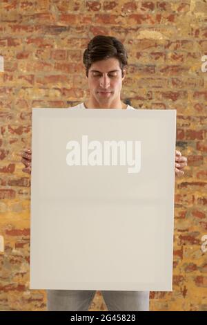 Tela vuota tenuto di fronte a un muro di mattoni Foto Stock