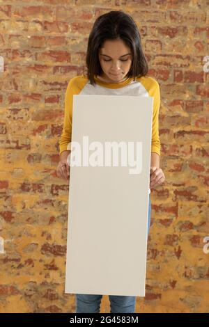 Tela vuota tenuto di fronte a un muro di mattoni Foto Stock