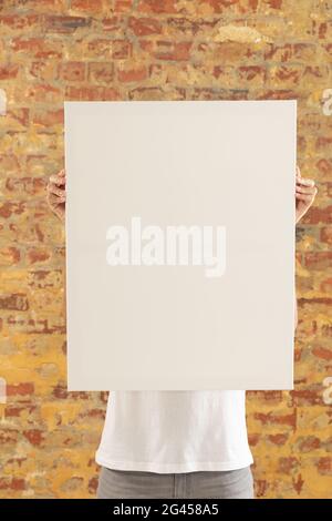 Tela vuota tenuto di fronte a un muro di mattoni Foto Stock