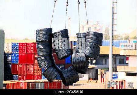 Una gru sta scaricando i prodotti in filo da una nave nel porto di Lomé, Togo, destinata ai mercati dell'Africa occidentale, mentre i container sono impilati sullo sfondo. Foto Stock