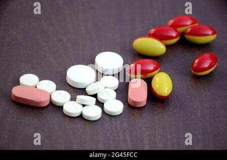 closeup mazzo il rosa, bianco con rosso, giallo di colore compresse di piccole medicine, capsula di cure mediche concetto isolato su sfondo viola. Foto Stock