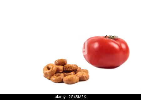 Un mucchio di tarallini, uno spuntino italiano di grano integrale e un pomodoro isolato su sfondo bianco. L'immagine contiene spazio per la copia Foto Stock