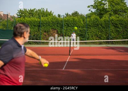 Pensionati che giocano a tennis, anziani che si divertono a tennis all'aperto, stile di vita Foto Stock