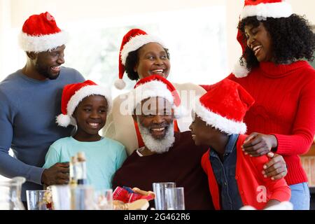 Famiglia afro-americana di generazione che sorride e indossa cappelli santa Foto Stock