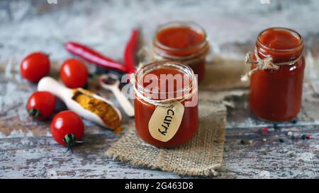 Salsa di curry fatta in casa. Vasetti con salsa di curry, pomodori, condimenti. Foto Stock