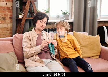 Nonna insegna al suo adorabile nipote come lavorare a maglia Foto Stock