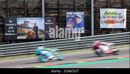 Hohenstein Ernstthal, Germania. 19 giugno 2021. Motorsport/Moto, Gran Premio di Germania, Moto3 al Sachsenring: Due piloti attraversano la curva di Ralf Waldmann durante la terza prova libera, che presenta anche un banner per Jason Ducasquier (M) del CarXpert PrüstelGP Team, morto il 30 maggio 2021. Ducasquier si era schiantato il 29 maggio 2021 nelle qualifiche Moto3 per il Gran Premio d'Italia e un giorno dopo ha ceduto alle sue ferite. PrüstelGP è una scuderia tedesca con sede a Oberlungwitz, in Sassonia. Credit: Jan Woitas/dpa-Zentralbild/dpa/Alamy Live News Foto Stock